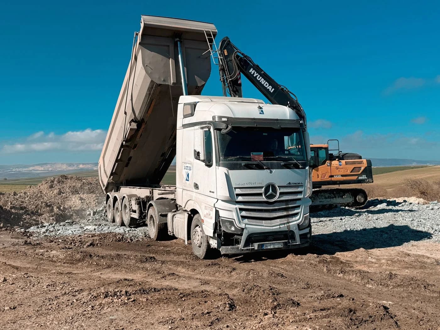 Un camion benne chargé par une pelle hydraulique sur un chantier de terrassement